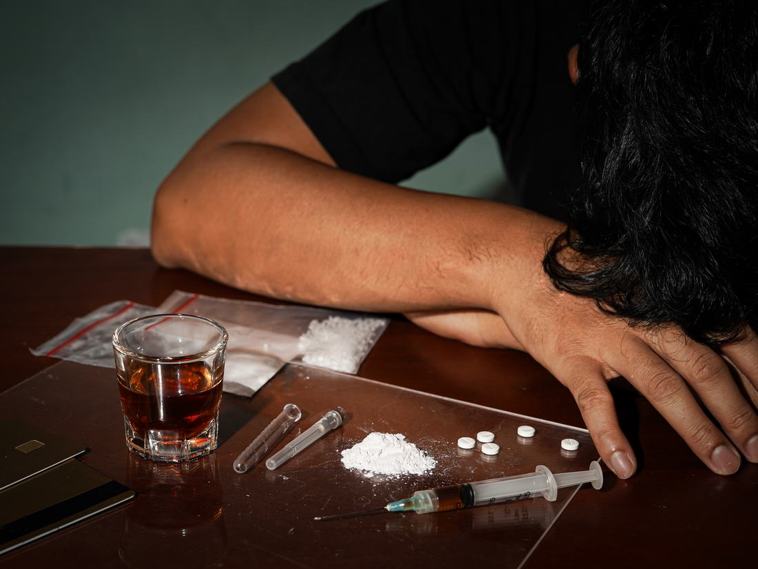 Spirits, syringes and powder left on a table beside someone who has collapsed