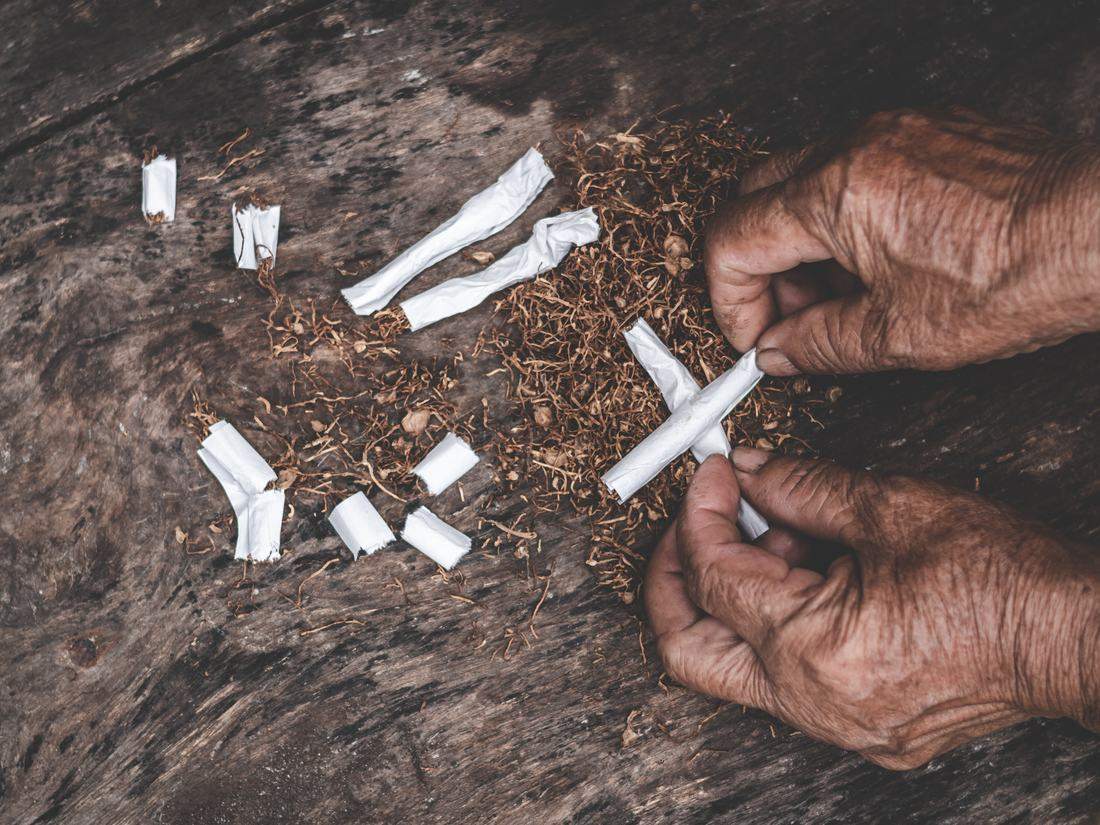 Weathered hands with loose tobacco and hand-rolled cigarettes
