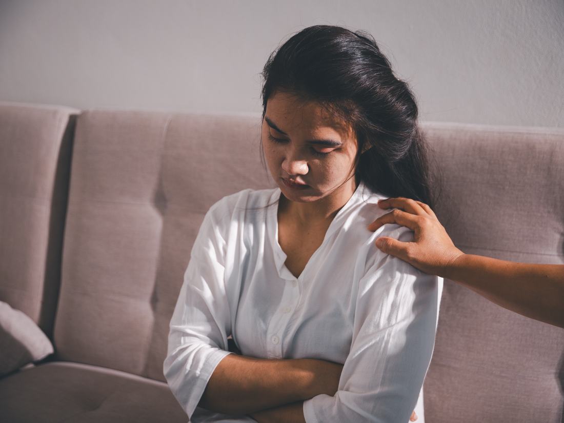 A woman turned away during a difficult conversation, a hand on her shoulder